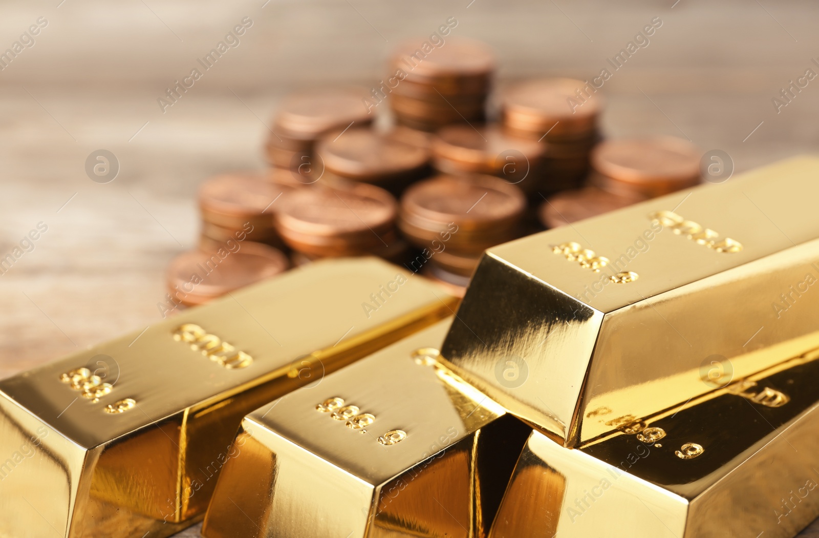 Photo of Shiny gold bars and coins on table, closeup