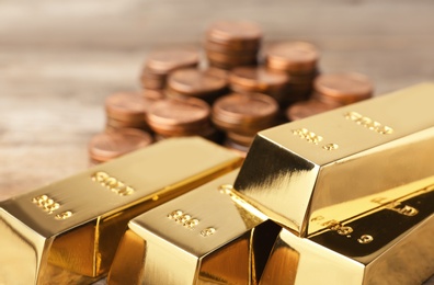 Shiny gold bars and coins on table, closeup