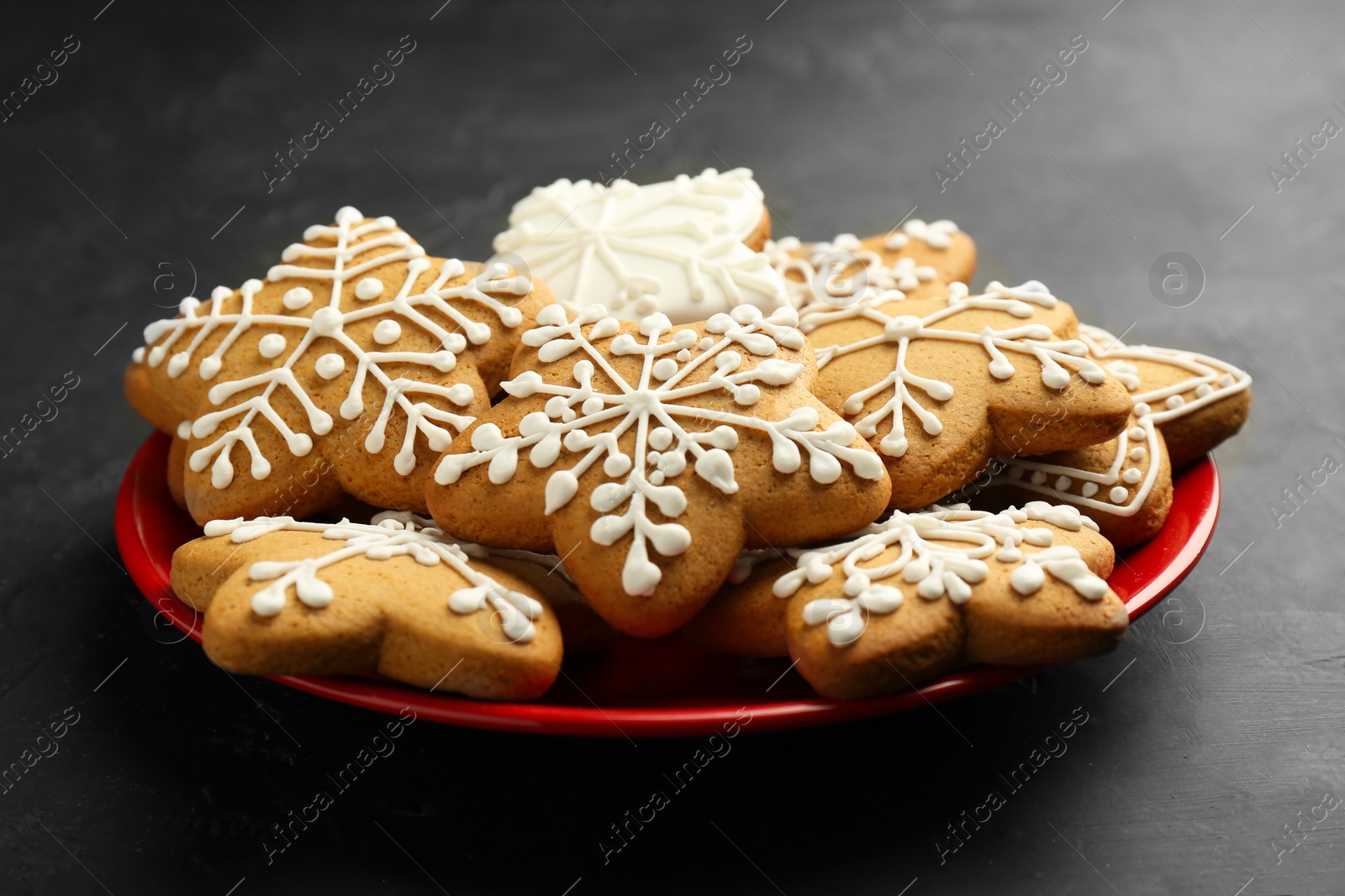 Photo of Tasty Christmas cookies with icing on black table, closeup