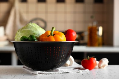 Photo of Metal colander with different wet vegetables on white textured table