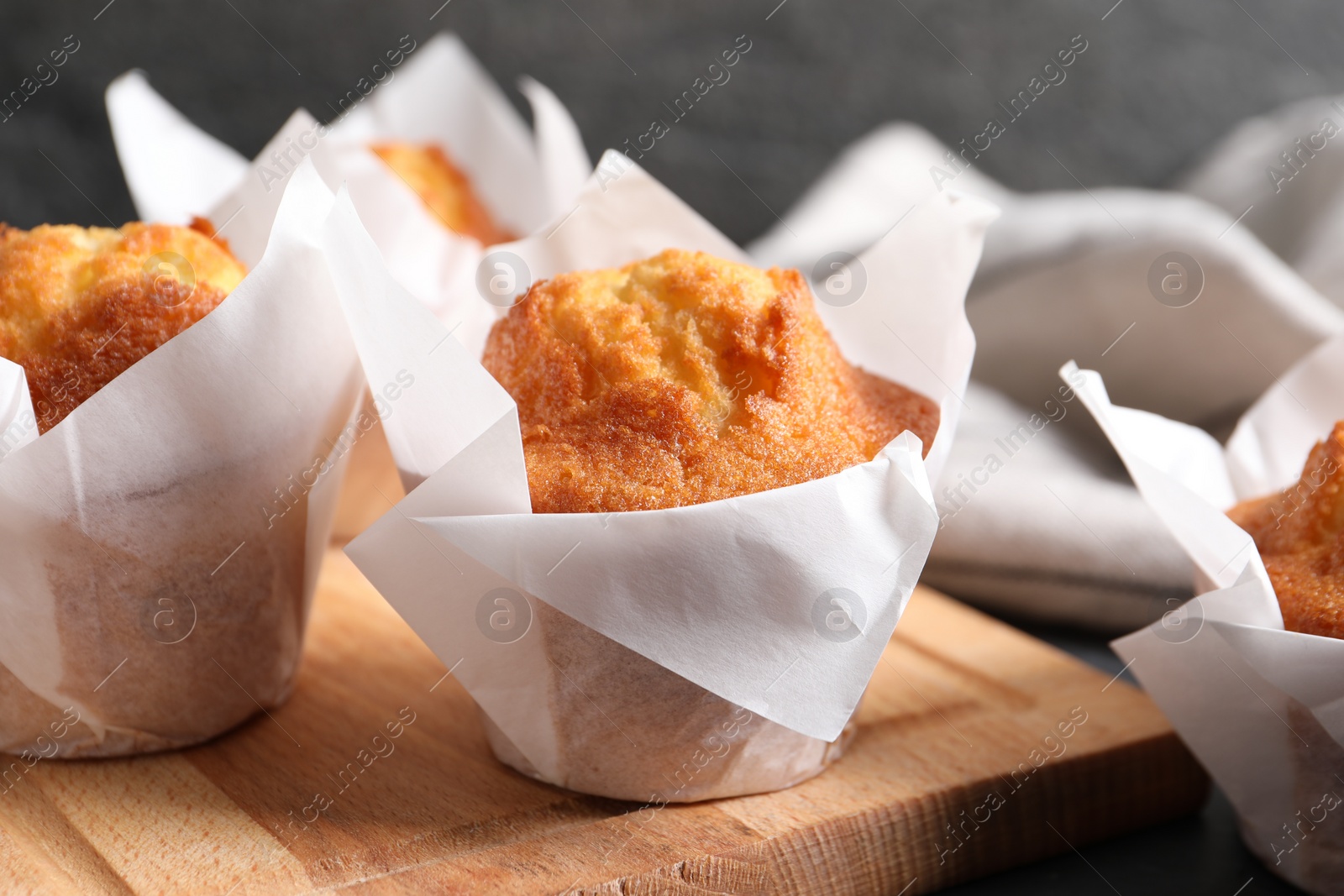 Photo of Tasty muffins on wooden board, closeup. Fresh pastry