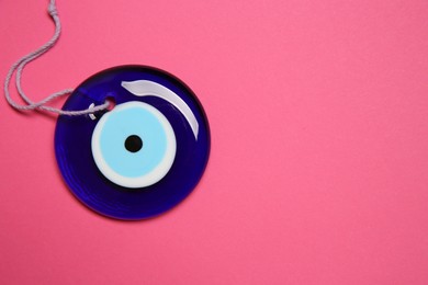 Photo of Evil eye amulet on pink background, top view. Space for text