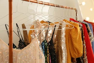 Stylish party dresses on rack indoors, closeup