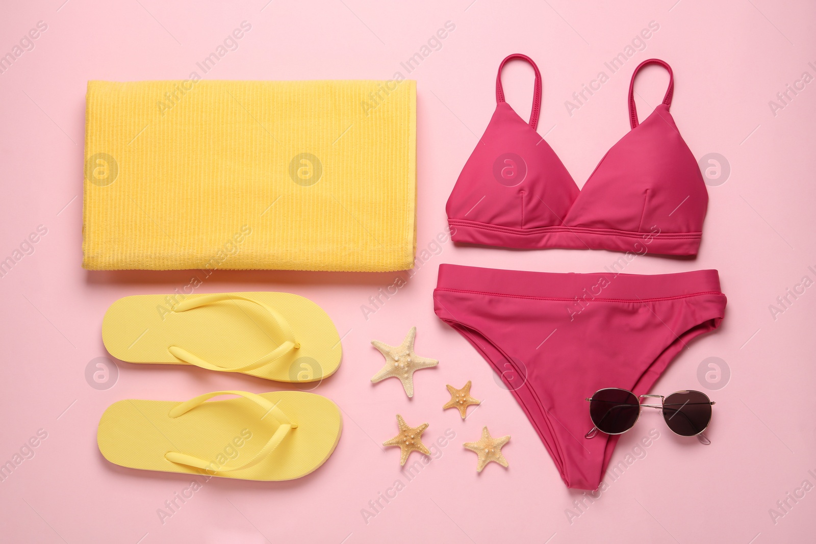 Photo of Stylish bikini and beach accessories on pink background, flat lay