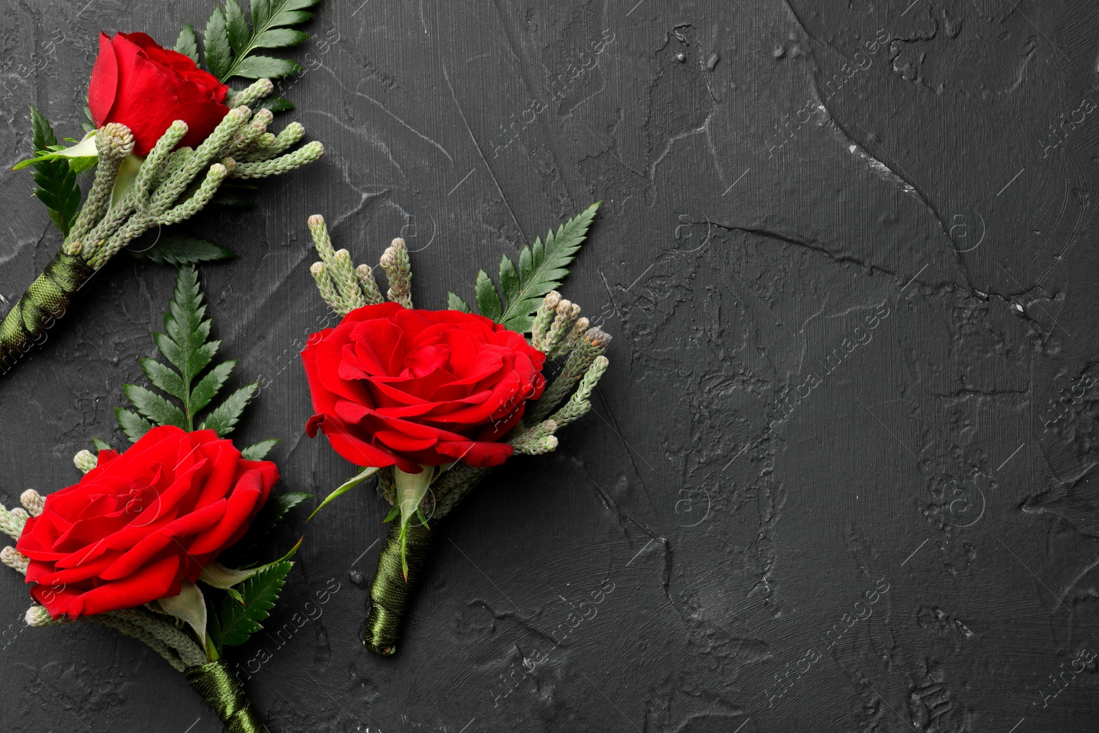 Photo of Many stylish red boutonnieres on black table, flat lay. Space for text