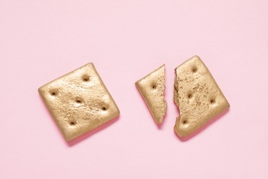 Photo of Golden whole and cracked cookies on light pink background, flat lay