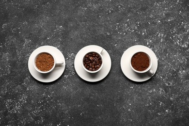 Photo of Cups with different types of coffee on dark grey table, flat lay