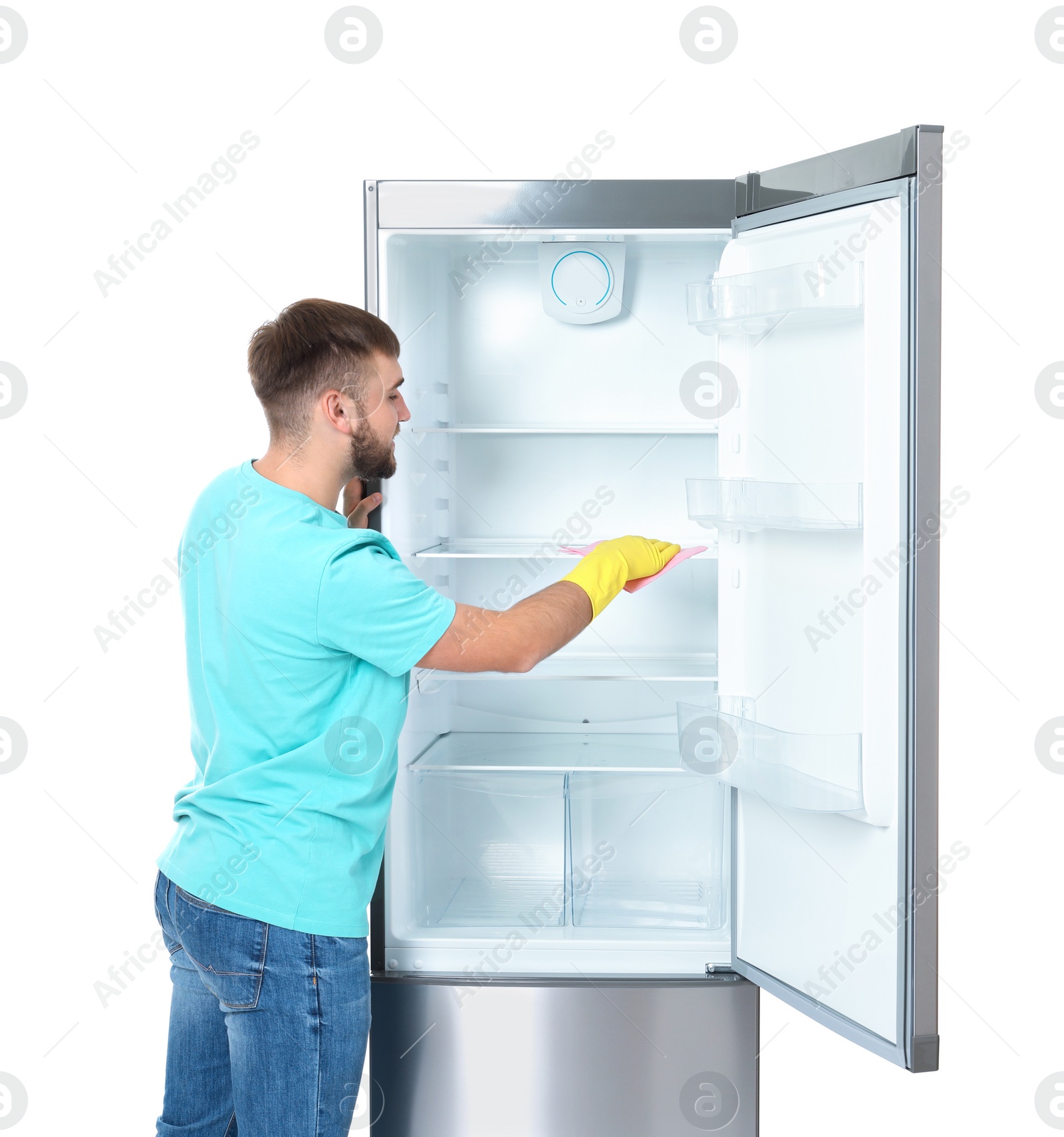 Photo of Young man cleaning refrigerator with rag on white background