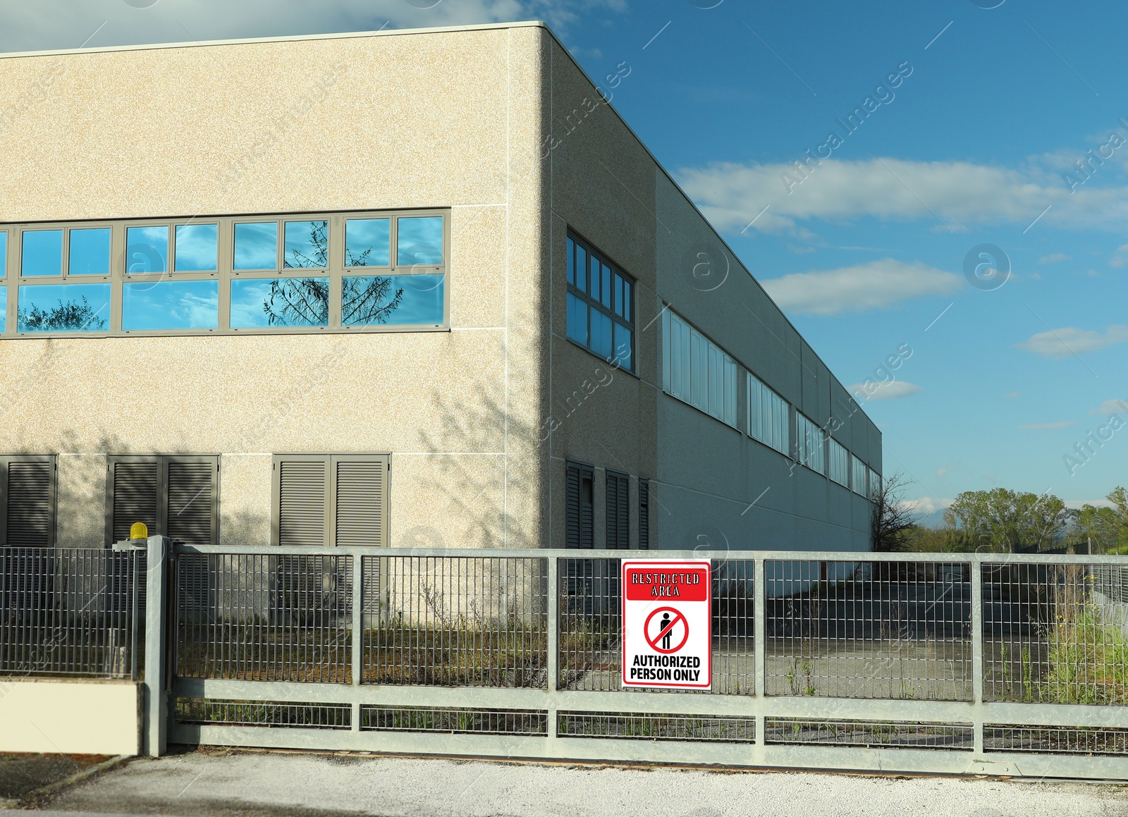 Image of Sign with text Restricted Area Authorized Person Only on fence near factory building outdoors