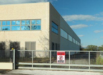 Sign with text Restricted Area Authorized Person Only on fence near factory building outdoors