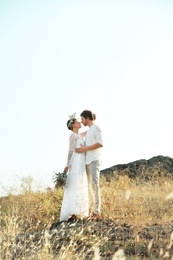 Happy newlyweds with beautiful field bouquet outdoors