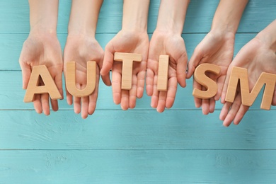 Photo of Group of people holding word "Autism" on wooden background