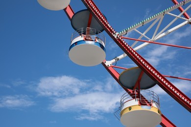 Photo of Beautiful large Ferris wheel against blue sky, low angle view