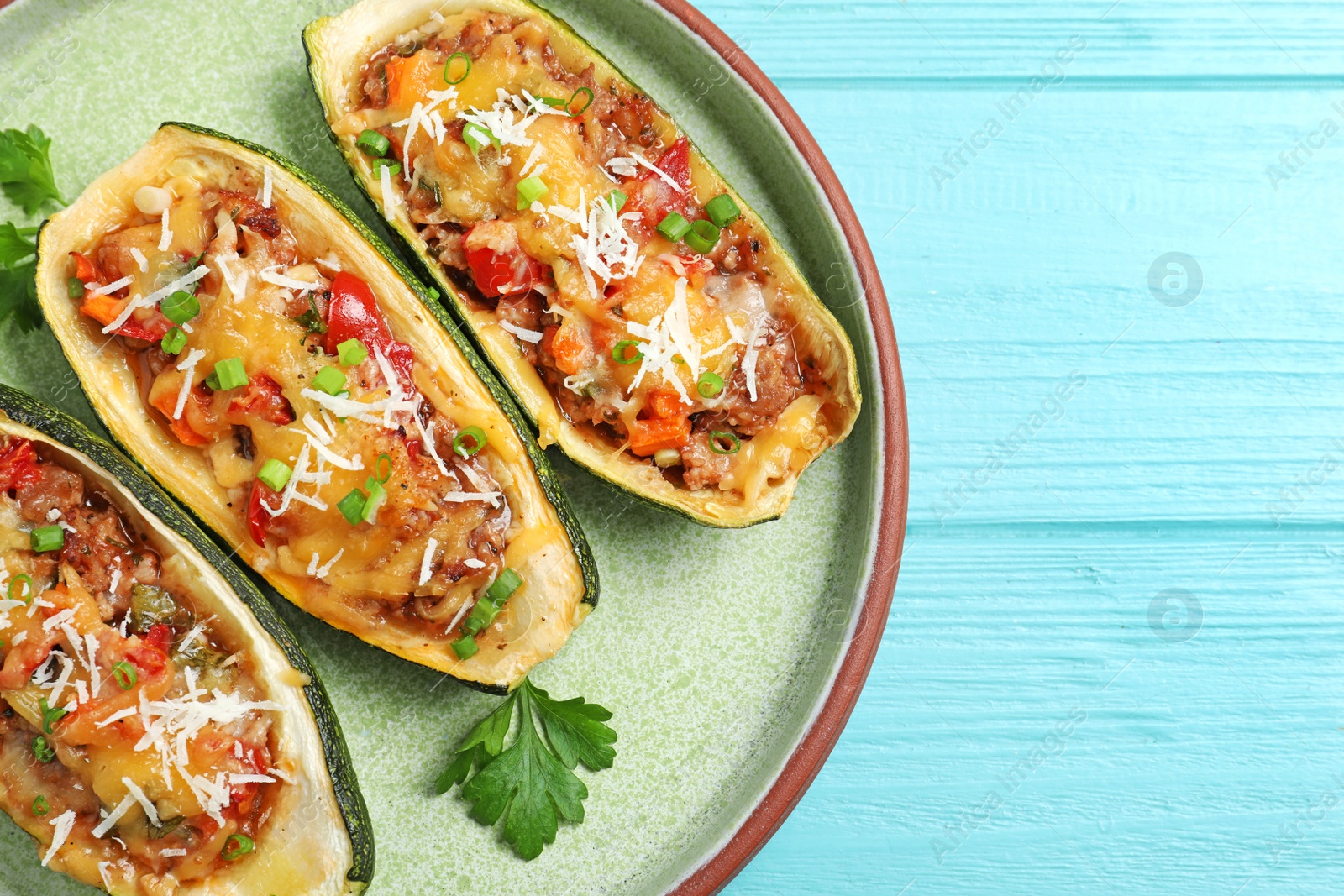 Photo of Delicious stuffed zucchini on light blue wooden table, top view. Space for text