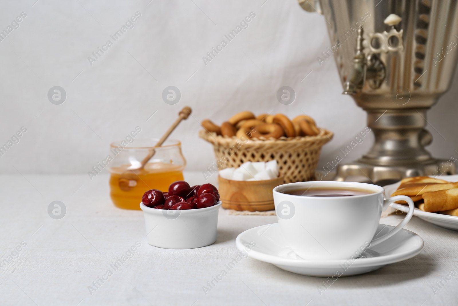 Photo of Aromatic tea, traditional Russian samovar and treats on table. Space for text