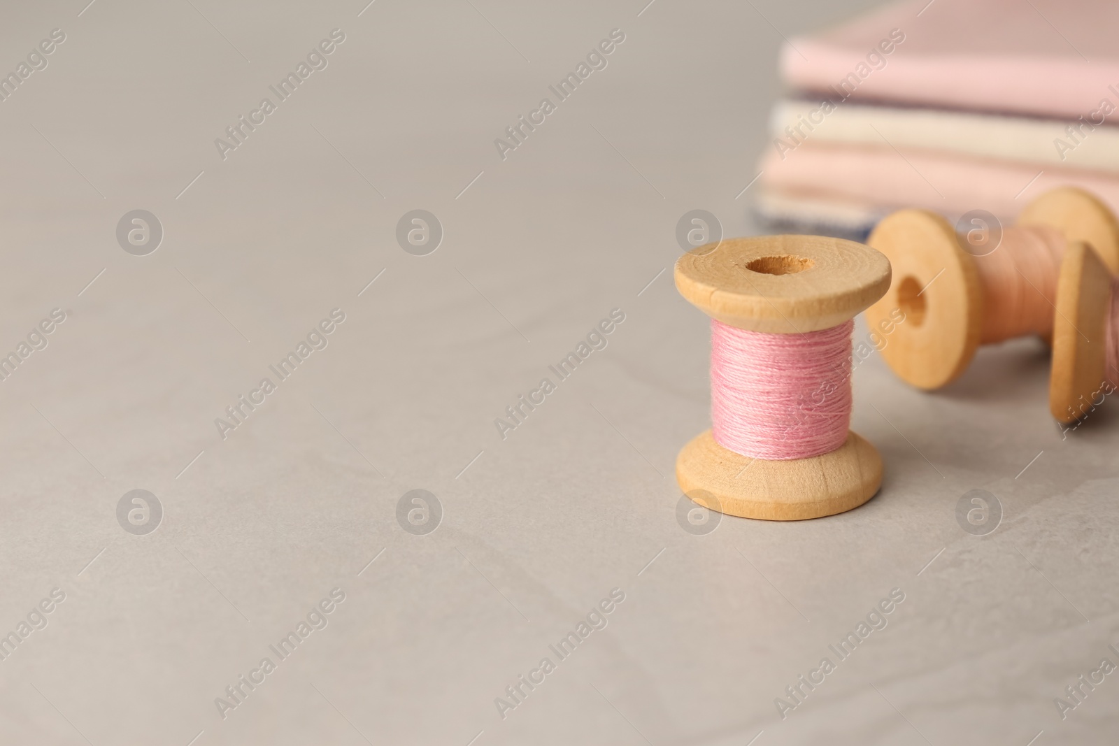 Photo of Set of color sewing threads on light grey table, space for text