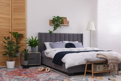 Photo of Stylish bedroom with double bed and beautiful green houseplants. Modern interior