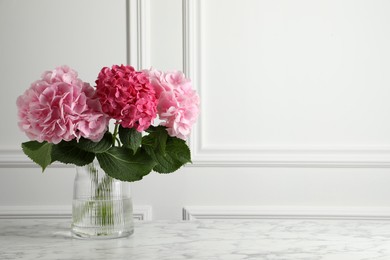 Vase with beautiful hortensia flowers on white marble table. Space for text