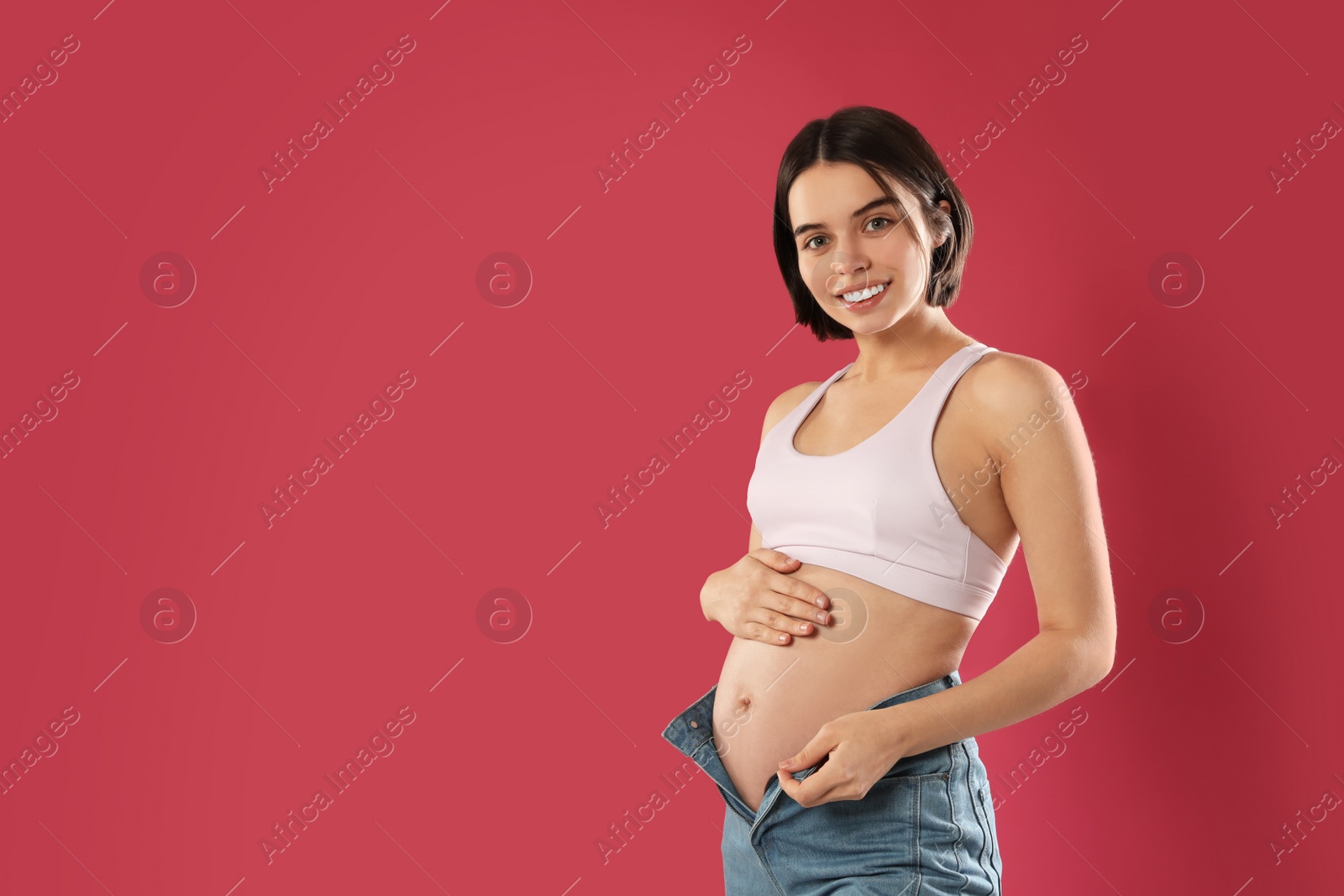 Photo of Happy young pregnant woman on red background, space for text