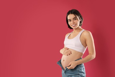 Photo of Happy young pregnant woman on red background, space for text