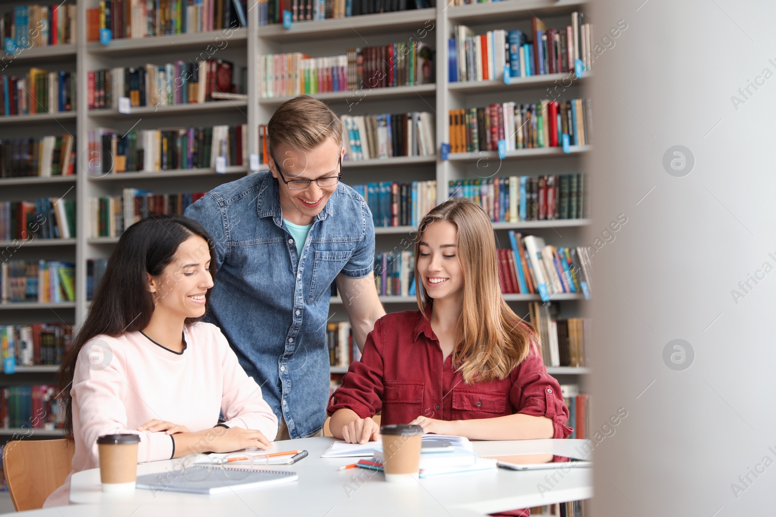 Photo of Young people discussing group project at table in library