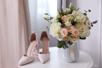 Beautiful wedding bouquet and shoes on white table indoors