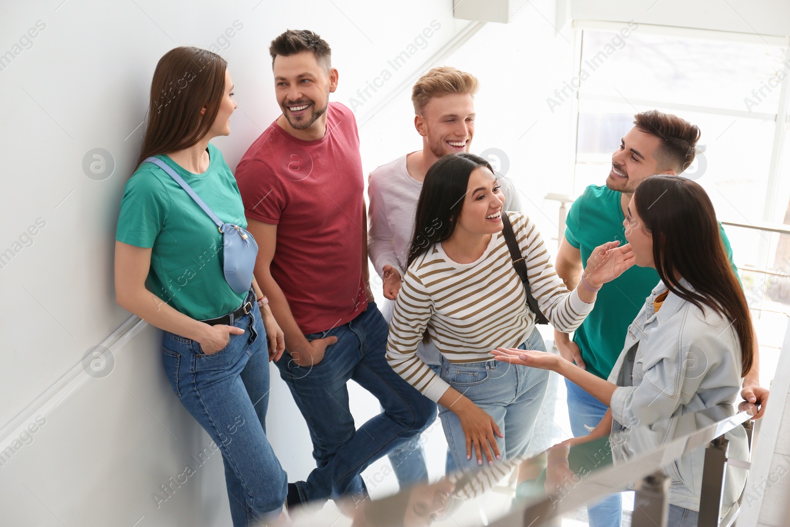 Photo of Group of happy people going up stairs indoors