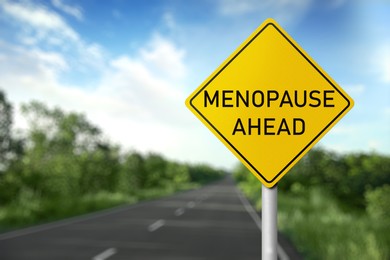 Concept of impending climacteric. Sign MENOPAUSE AHEAD near asphalt road outdoors