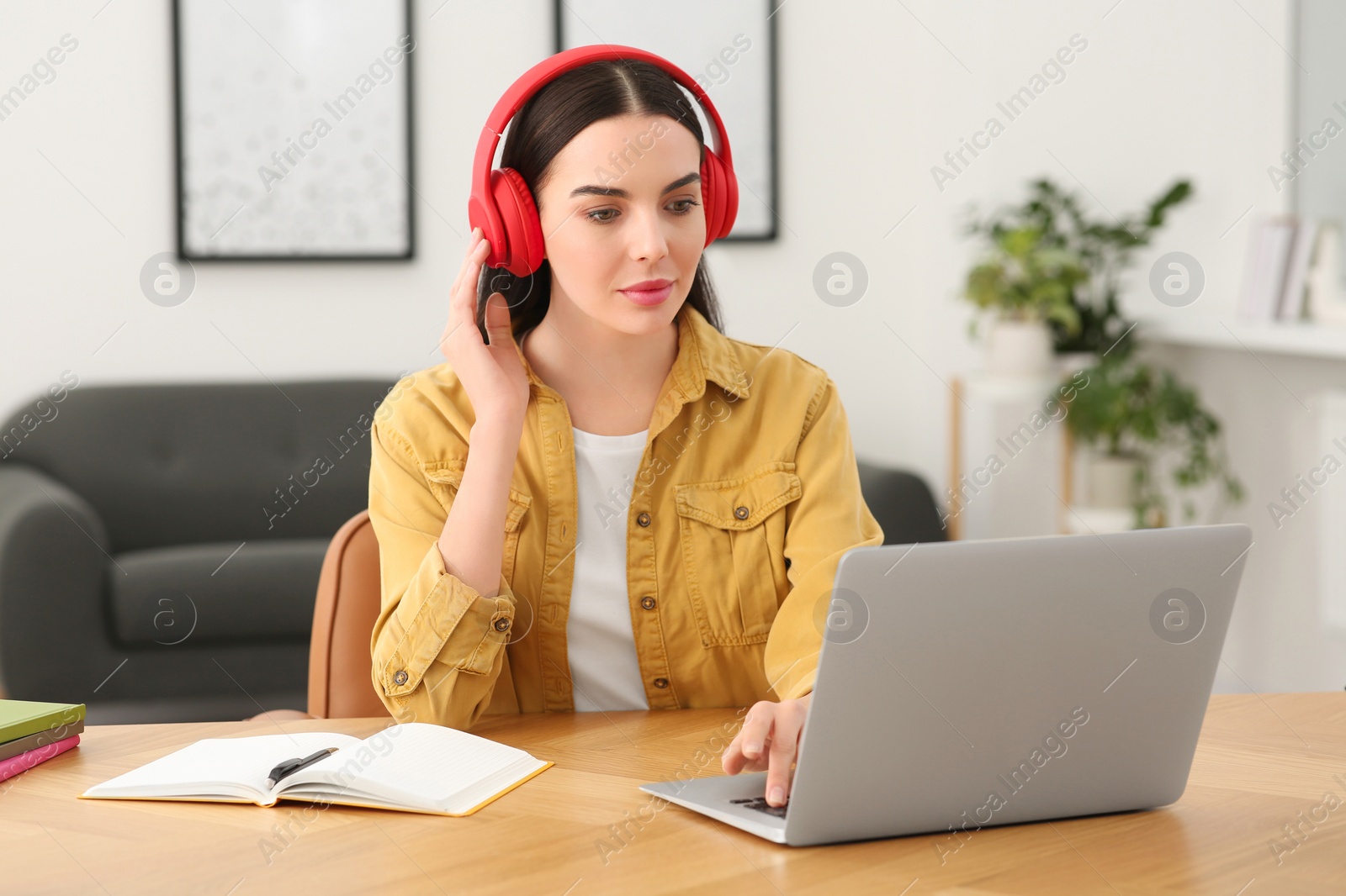 Photo of Woman in headphones studying on laptop at home. Online translation course