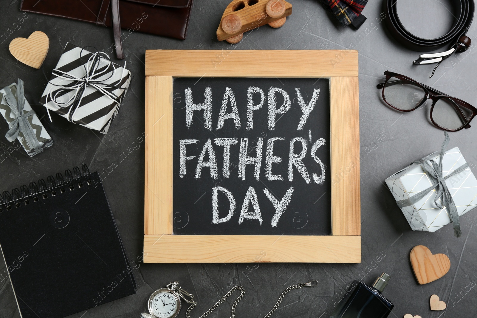 Photo of Chalkboard with phrase HAPPY FATHER'S DAY and male accessories on stone background, flat lay