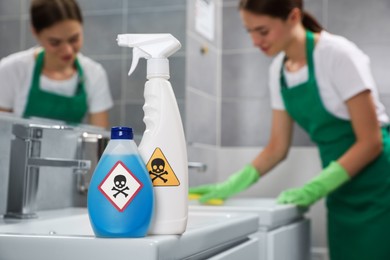 Photo of Bottle and spray of toxic household chemical with warning signs in bathroom