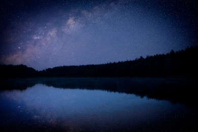 Image of Amazing starry sky and trees reflecting in lake at night