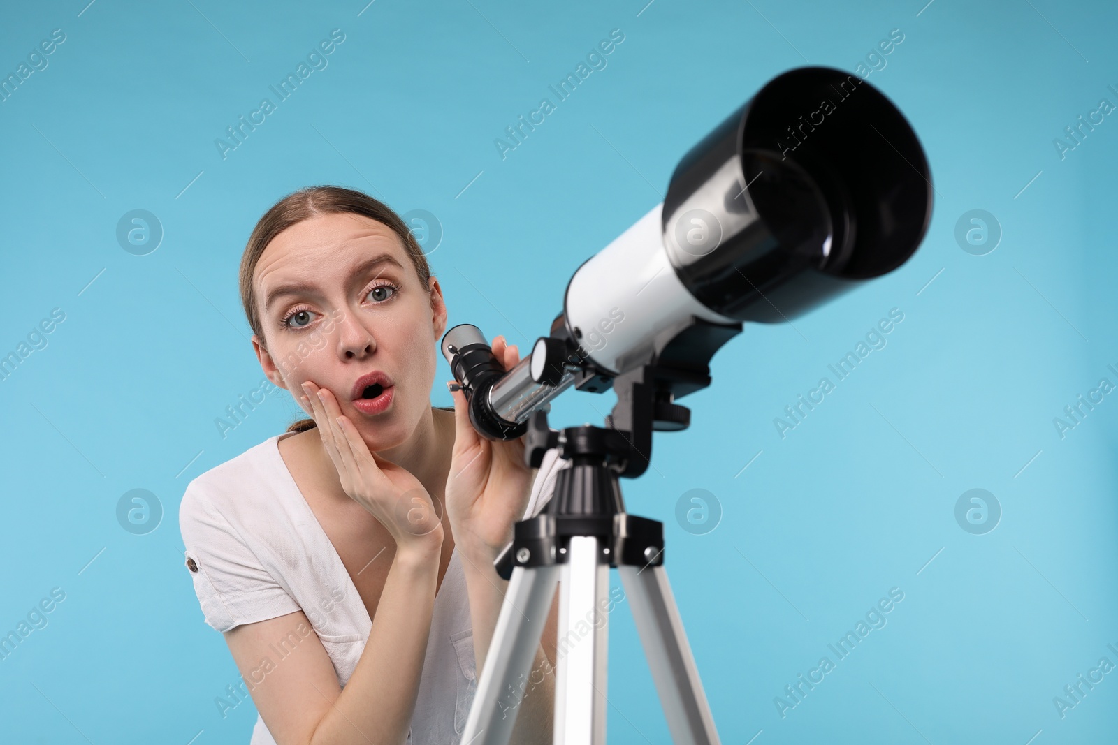 Photo of Surprised astronomer with telescope on light blue background