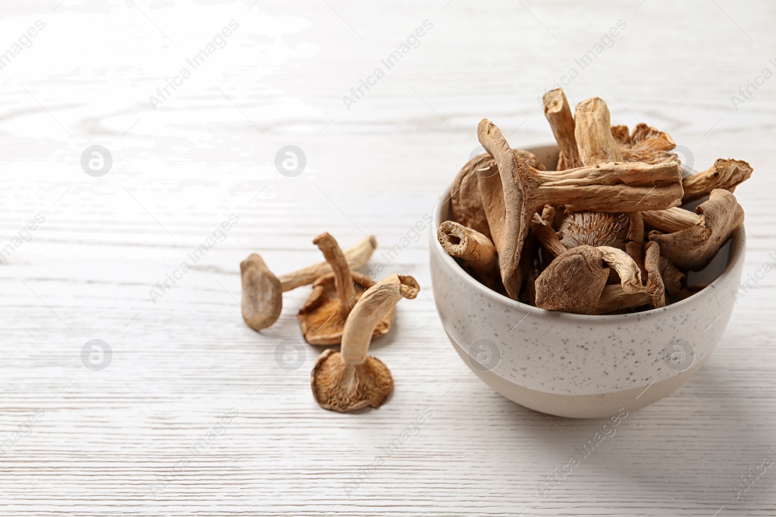 Photo of Bowl of dried mushrooms on wooden background. Space for text