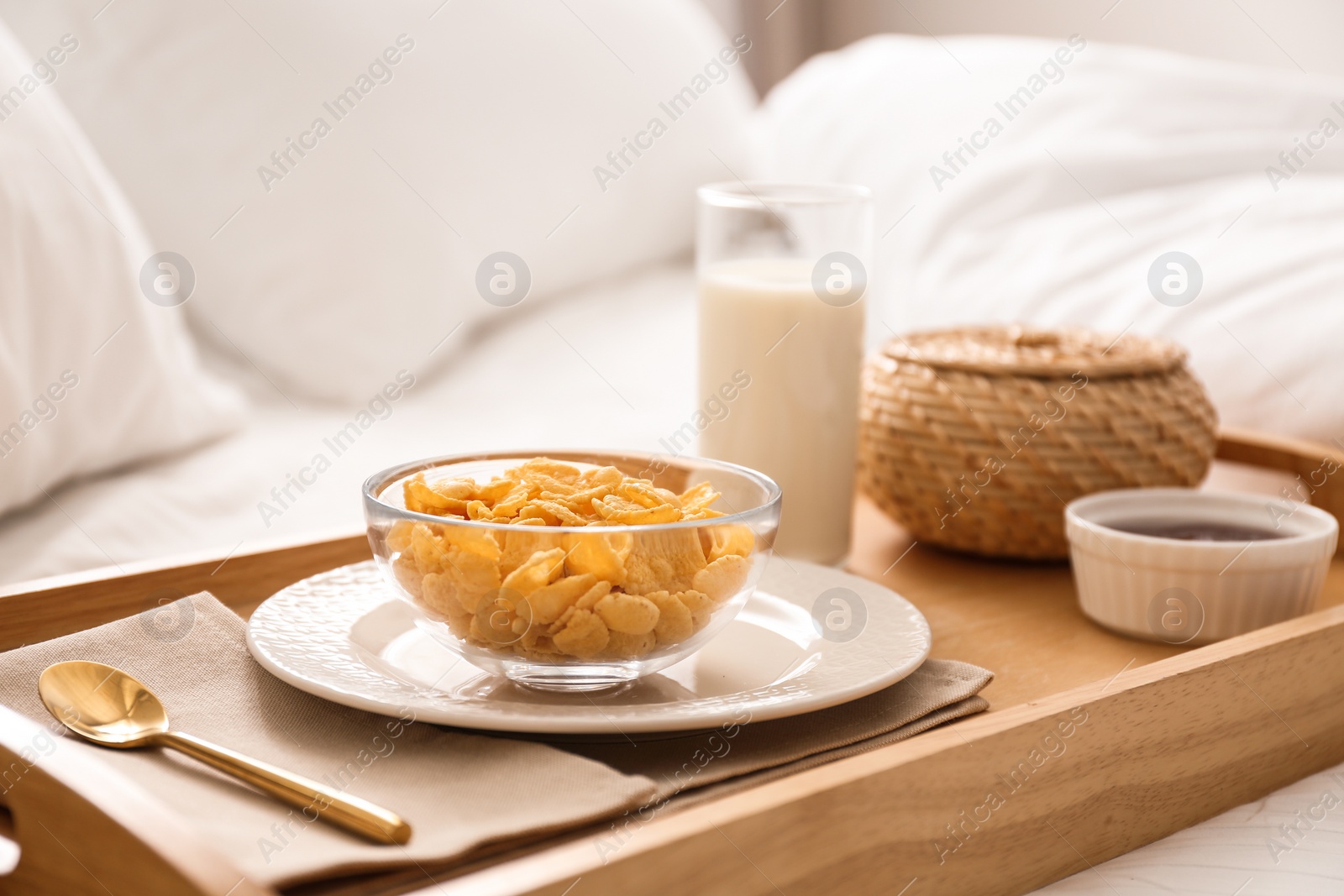 Photo of Corn flakes and milk in tray on bed.  Delicious morning meal