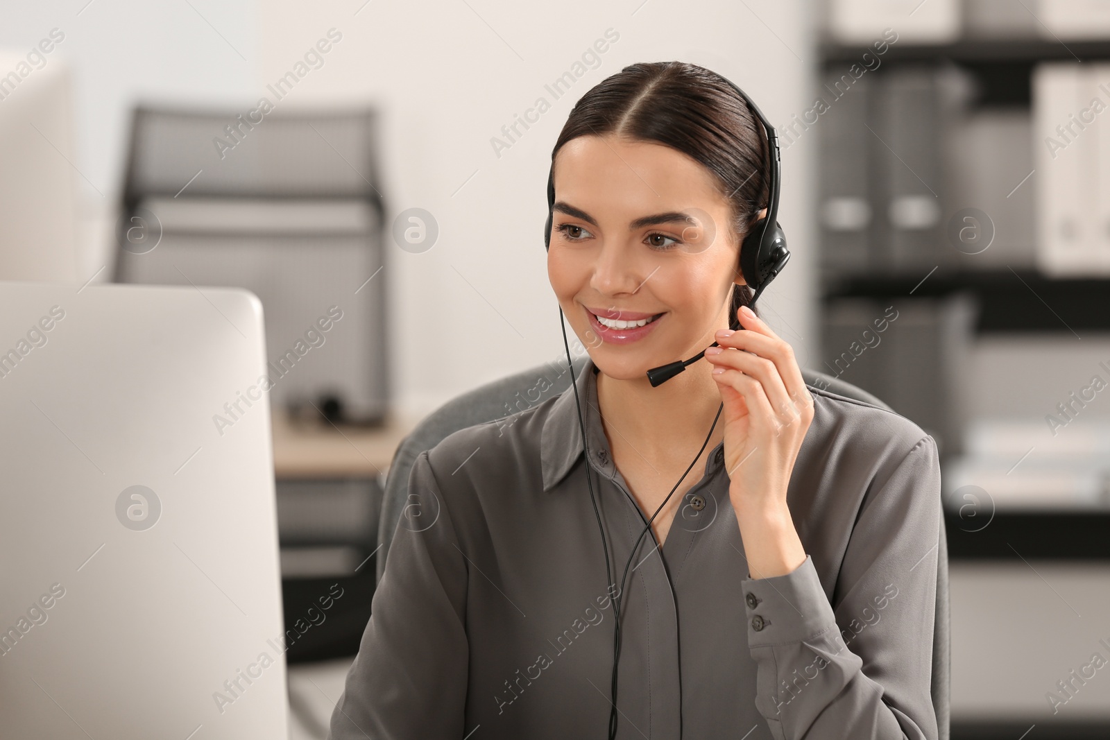 Photo of Hotline operator with headset working on computer in office