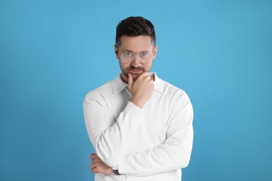 Portrait of man in stylish glasses on light blue background