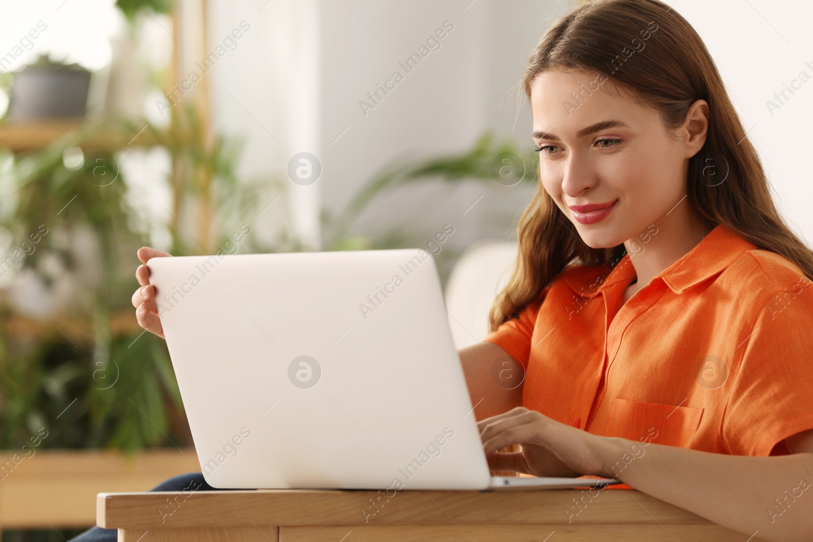 Photo of Happy young woman with laptop at home