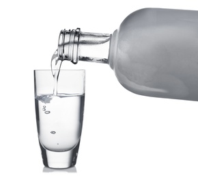 Pouring cold vodka into shot glass on white background