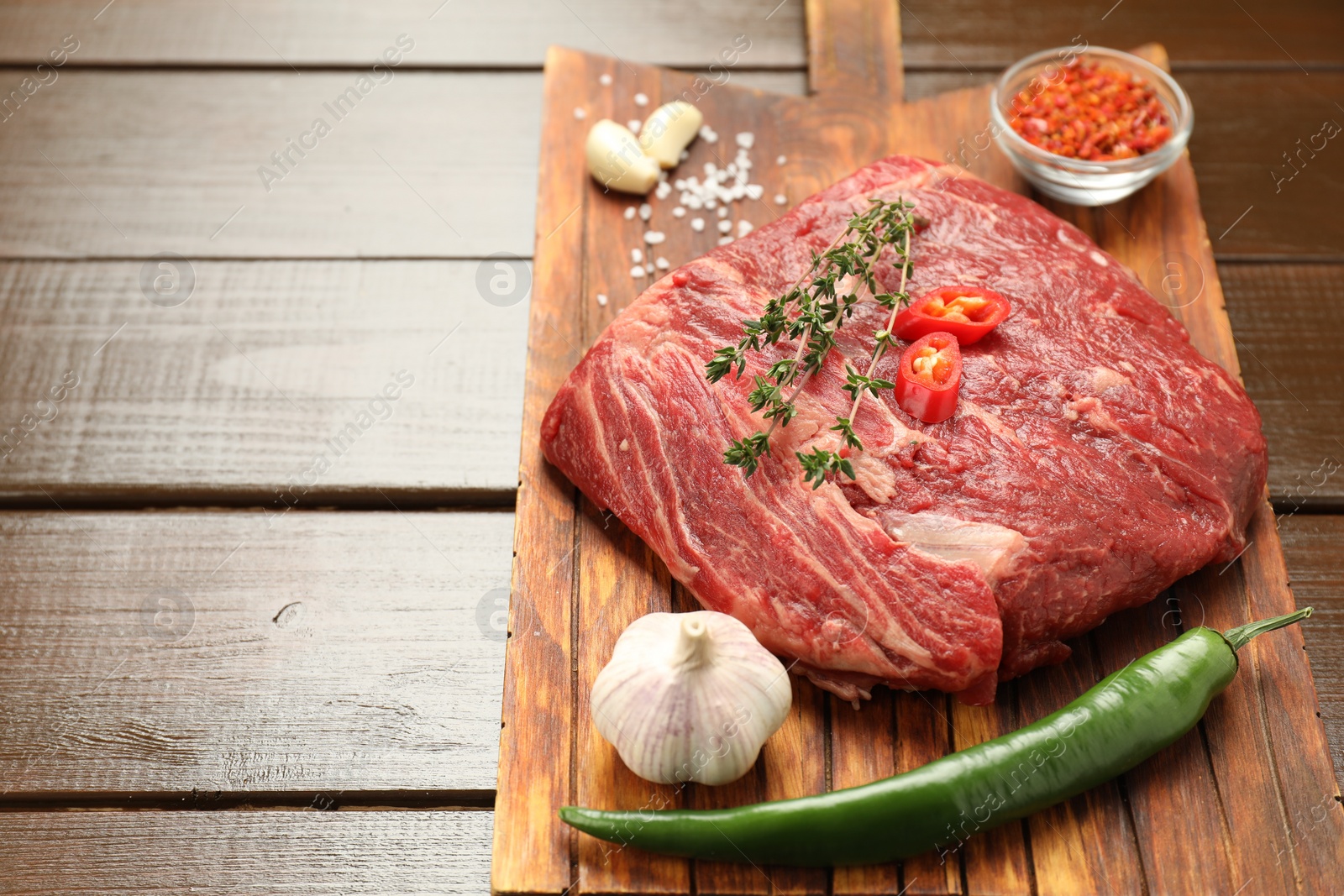 Photo of Fresh raw beef cut with spices on wooden table. Space for text