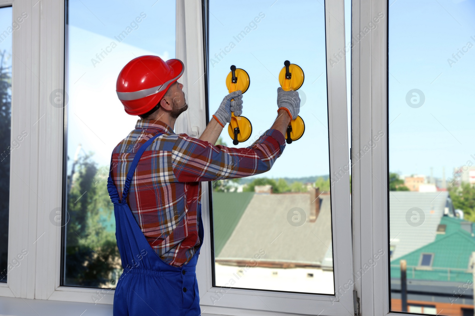 Photo of Worker using suction lifters during plastic window installation indoors