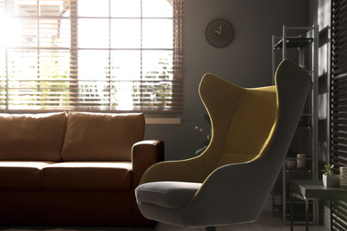 Stylish living room interior with comfortable armchair and leather sofa