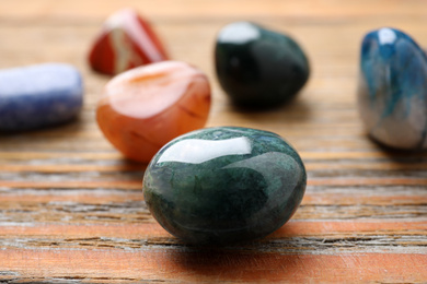 Photo of Beautiful gemstones on wooden table, closeup. Healing crystals