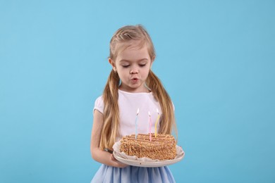 Photo of Birthday celebration. Cute little girl holding tasty cake with burning candles on light blue background