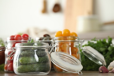 Photo of Pickling jars with fresh vegetables on wooden table in kitchen