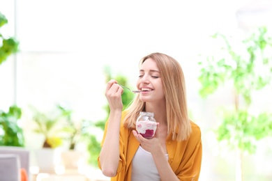 Young attractive woman eating tasty yogurt, indoors