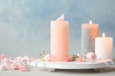 Photo of Candles with floral decor on table against color background