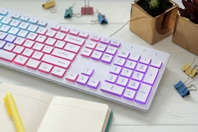 Photo of Modern RGB keyboard and office stationery on white wooden table