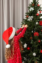 Little girl decorating Christmas tree at home