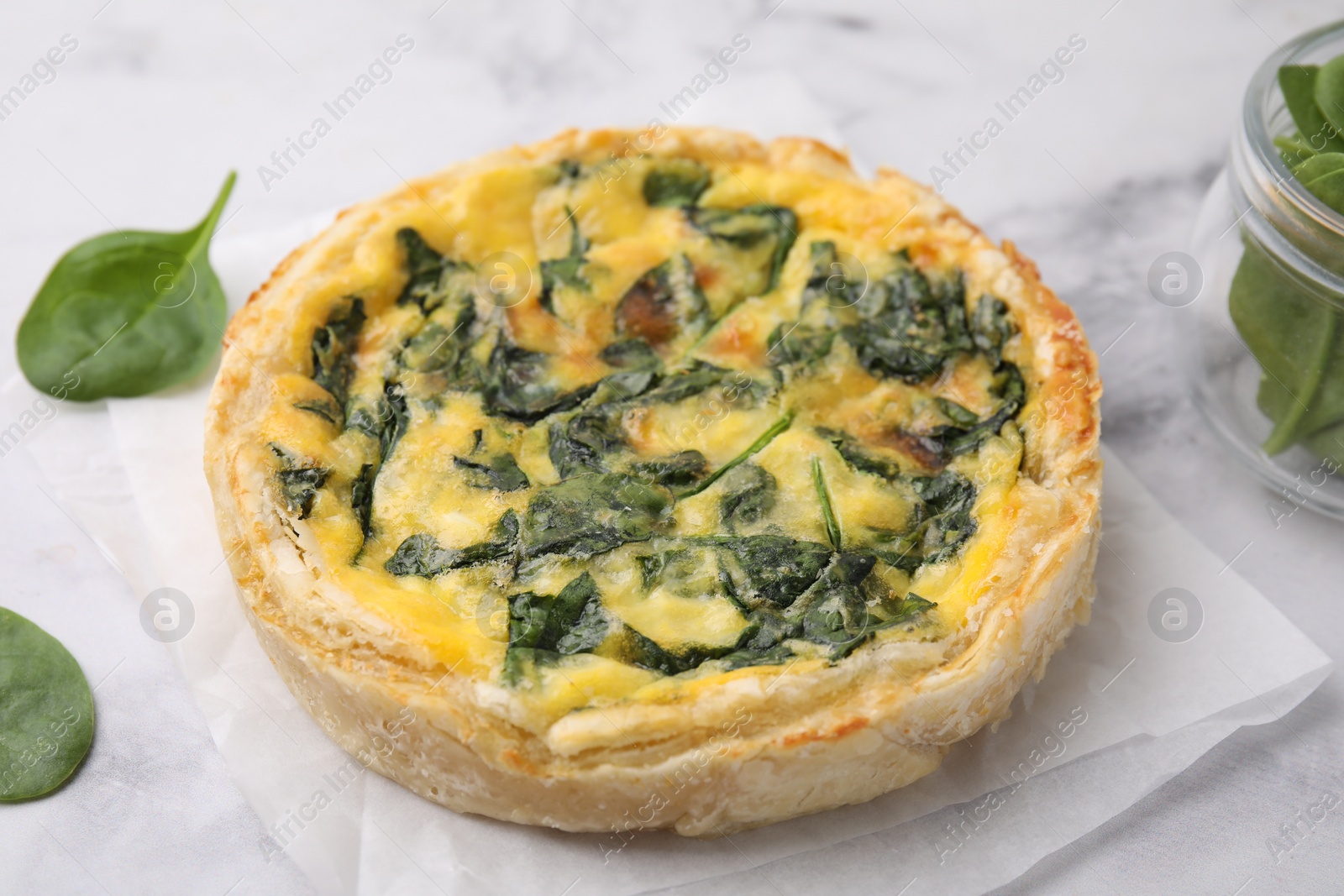 Photo of Delicious pie with spinach on white marble table, closeup